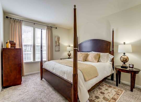 A bedroom with a large bed and a wooden dresser.