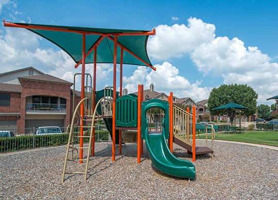 A playground with a green slide and a red and orange structure.