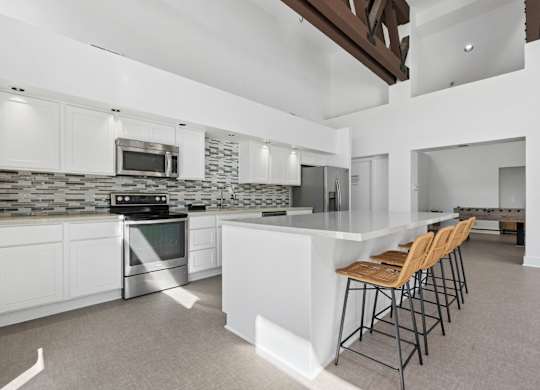 A modern kitchen with white cabinets and a stone backsplash.