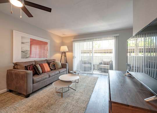 Apartments for Rent in San Clemente, CA - Rancho Del Mar - Furnished Living Room with Hardwood-Inspired Flooring, Stylish Decor, and a Sliding Glass Door to a Private Patio/Balcony