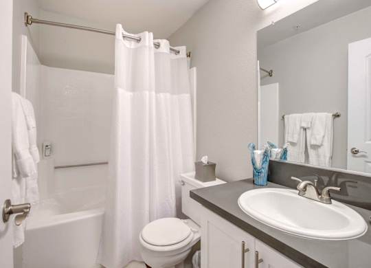 San Clemente Apartments for Rent - Rancho Del Mar - Bathroom with Granite Countertop Sink, White Cabinetry, Large Mirror, and Shower/Tub Combo with Shower Curtain.