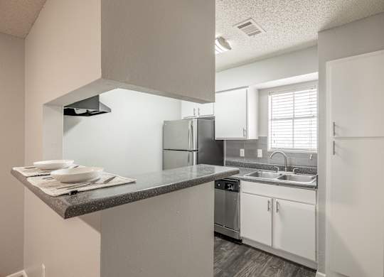 A kitchen with white cabinets and a black counter top.