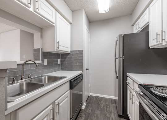 A kitchen with white cabinets and a black refrigerator.