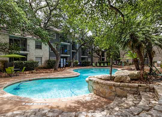 A pool surrounded by trees and a stone wall.
