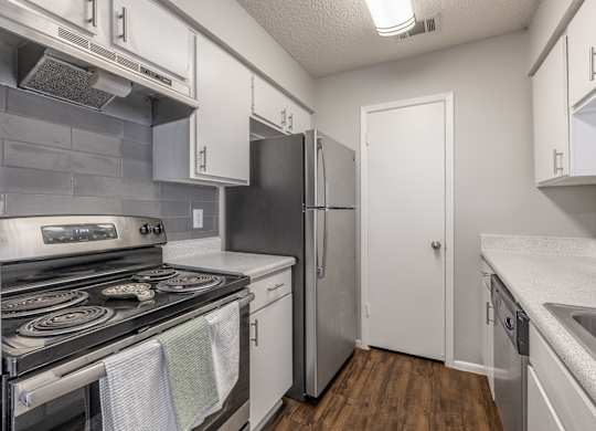 A kitchen with a stove, refrigerator, and sink.
