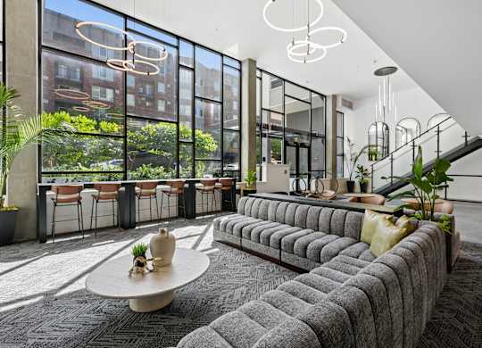A modern living room with a large grey sofa and a round table with a vase on it.