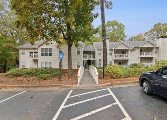 A car is parked in a parking lot in front of apartment buildings.