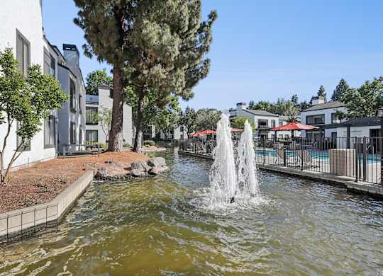 A fountain in the middle of a body of water surrounded by buildings.