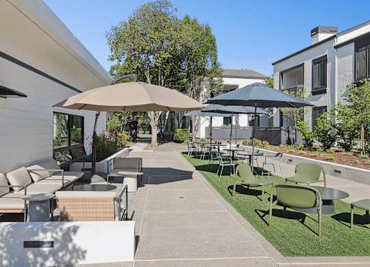 A patio with a table and chairs under umbrellas.
