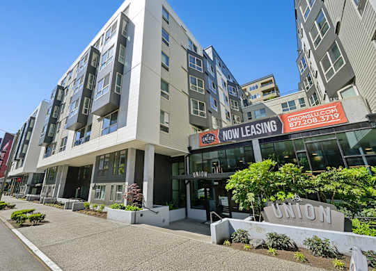 A modern apartment building with a leasing sign in front.