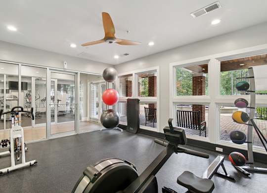 A gym with a variety of equipment including a stationary bike, a rowing machine, and a bench press.