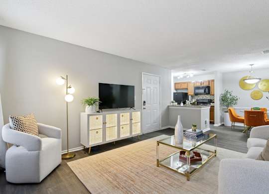 A living room with a white sofa, a white armchair, a white cabinet, a white TV, a white rug, a white floor, a white ceiling, a white wall, a white door, a white table, a white
