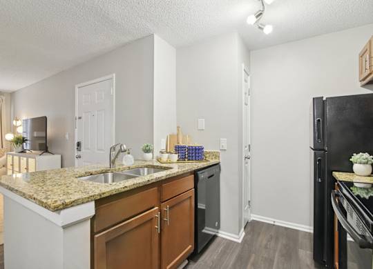 A kitchen with a granite countertop and a black refrigerator.
