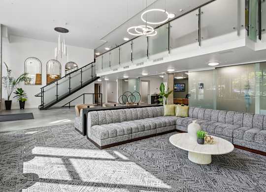 A modern office lobby with a staircase, couches, and a coffee table.