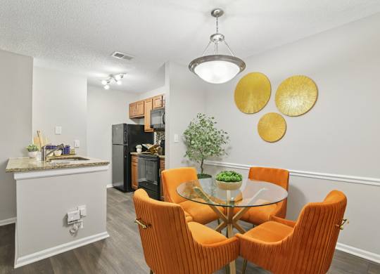 A dining room with a glass table and orange chairs.