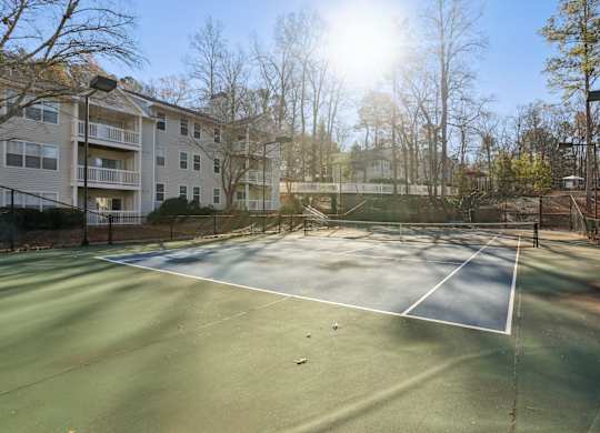 A tennis court is surrounded by apartment buildings.