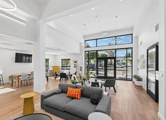 A modern living room with a grey couch and a yellow stool.