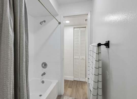 A white bathroom with a shower curtain and a white door.