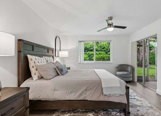A bedroom with a bed, chair, and a ceiling fan.