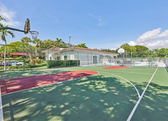 A basketball court with a red and green surface and a basketball hoop.