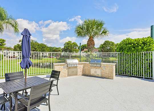A patio with a table and chairs and a blue umbrella.