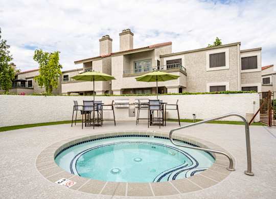 Apartment Scottsdale, AZ - The Sycamore at Scottsdale - An exterior view the spa featuring lounge seating, umbrellas, and grills