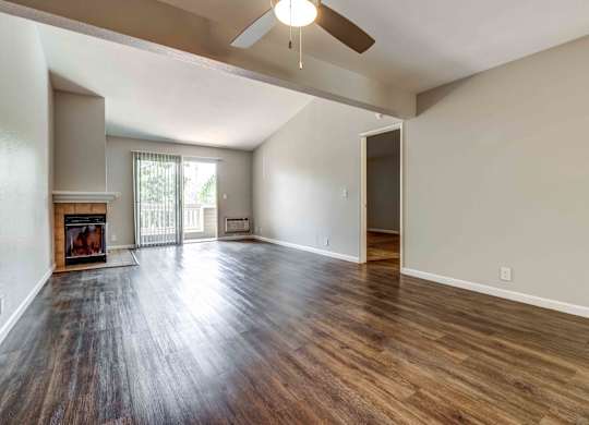 Apartments For Rent In San Jose, CA - Terra House - Living Room With Ceiling Fan, Hardwood-Inspired Flooring, Fire Place, And Direct Access To Patio