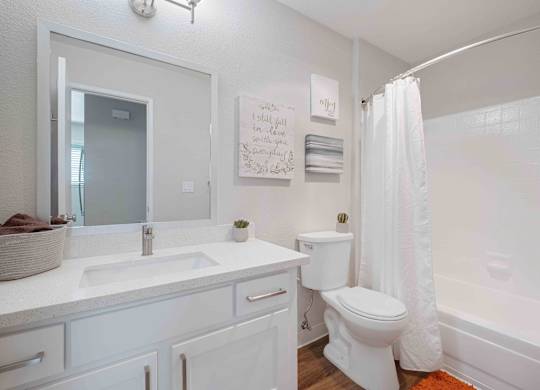 A white bathroom with a toilet, sink, and mirror.