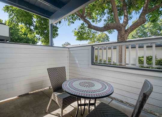 A patio with a table and chairs under a tree.