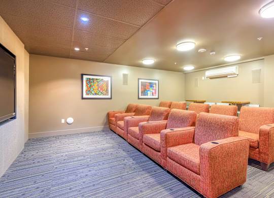 a spacious theater room with orange couches and a tv