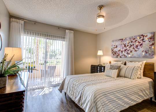 Pet-Friendly Apartments in Phoenix AZ - Village at Lakewood - Bedroom with Wood-Style Flooring and Access to Patio