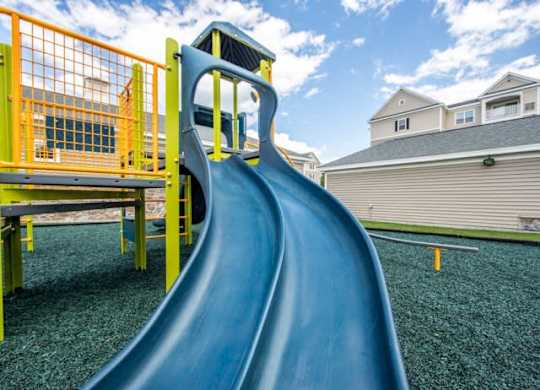 a slide in a playground with houses in the background