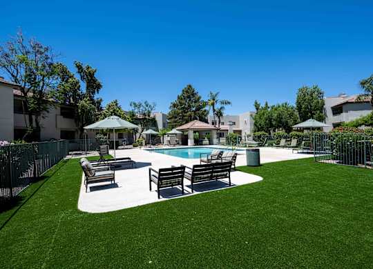 1-Bedroom Apartments in Ahwatukee, Phoenix, AZ - Village at Lakewood - Pool Area with Artifical Turf, Pool, Sundeck with Lounge Seats and Umbrellas.