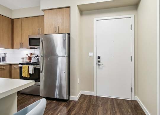 A kitchen with a refrigerator, microwave, and oven.