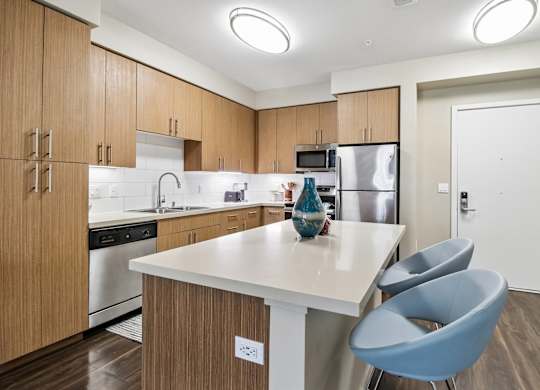 A kitchen with a white counter top and blue chairs.