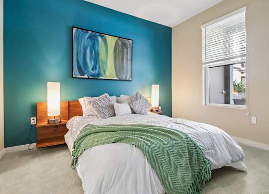 A bedroom with a bed, nightstands, and a painting on the wall.