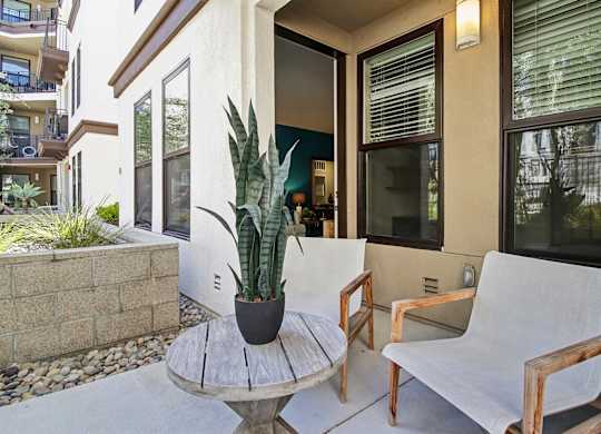 A white chair sits on a patio next to a table with a plant on it.