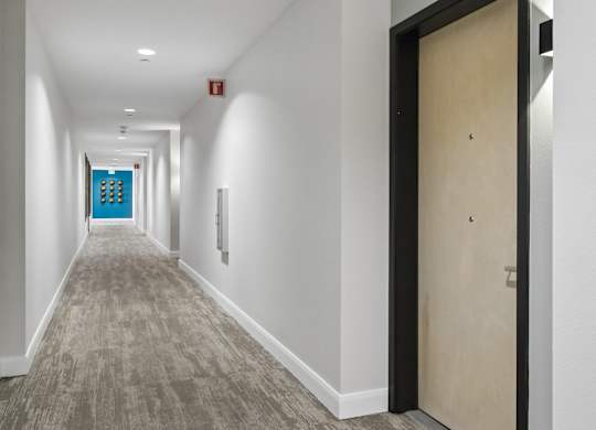 A long hallway with a blue door at the end.