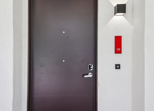 A black door with a silver handle and a red sign with the number 139 on it.