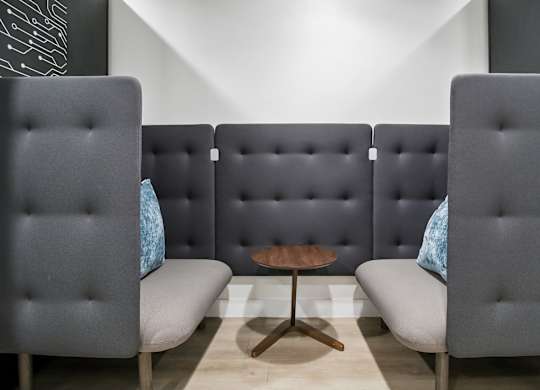 Three grey chairs with blue pillows are arranged in a row.