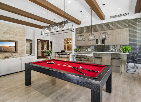 A pool table is in the middle of a room with a bar and a couch.