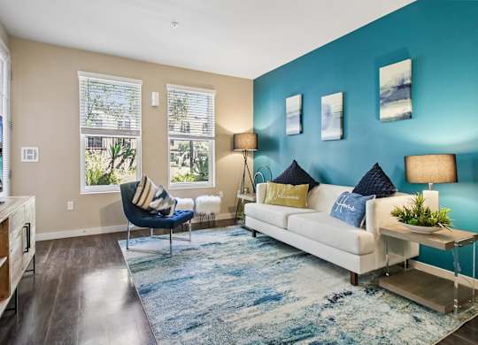 A living room with a blue accent wall and a white couch.
