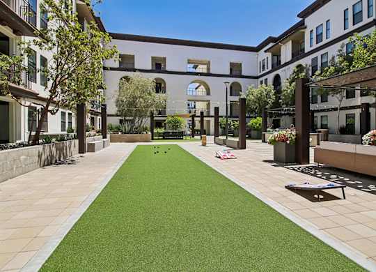 A courtyard with a green lawn and a building in the background.