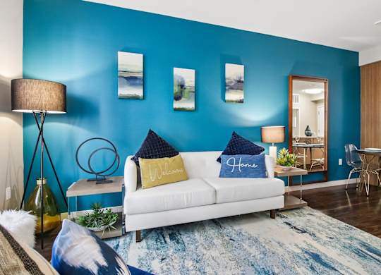 A living room with a white couch and a blue rug.