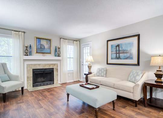 Apartments in Marietta Georgia for Rent – Wood Pointe Apartments - A living room with a fireplace, two couches, a chair, and a painting on the wall.