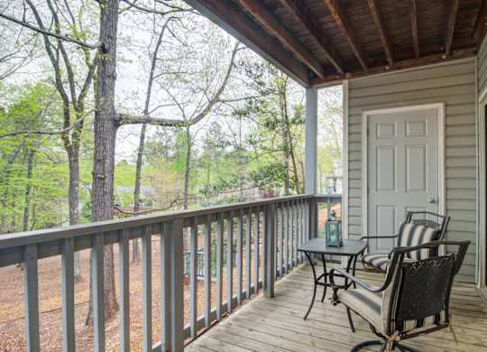 Pet-Friendly Apartments in Marietta– Wood Pointe Apartments – A porch with a table and chairs overlooking a wooded area.