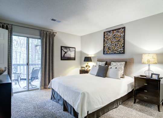 Apartments in Marietta Georgia for Rent – Wood Pointe Apartments - A bedroom with a large bed, a chair, and a painting on the wall.