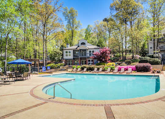 Apartments in Marietta Georgia for Rent – Wood Pointe Apartments - A large swimming pool surrounded by trees and a building in the background.