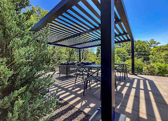 A patio with a table and chairs under a blue and white striped awning.