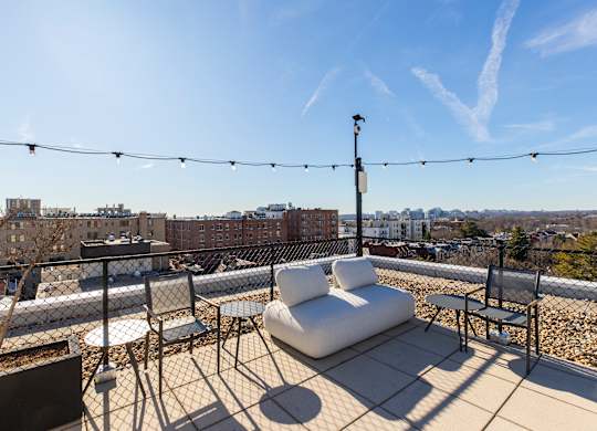 A rooftop patio with white furniture and string lights.